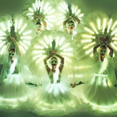 LED-Tänzerinnen tanzen mit leuchtenden Kostümen bei Outdoor-Event