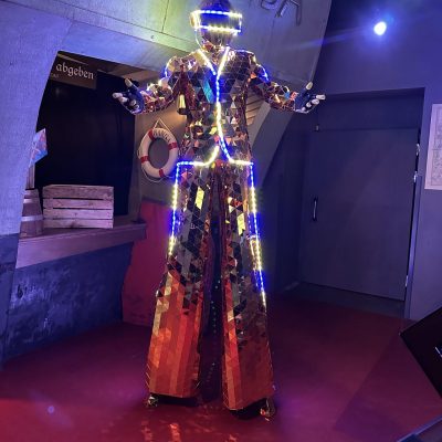 LED mirror stilt performer in a reflective costume entertaining guests at a night-time event or festival